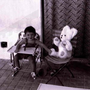 Niño en un patio con un osito de peluche