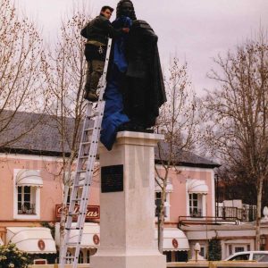 Un trabajador cubre la escultura del rey Fernando VI en Aranjuez