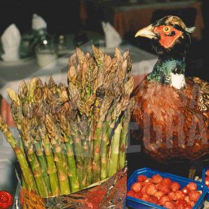 Un faisán, un manojo de espárragos verdes y varias cestitas de fresas en un restaurante