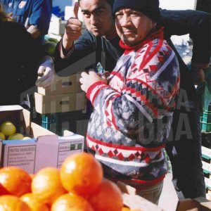 Tres personas en un puesto de venta de fruta en el Rastro de Aranjuez