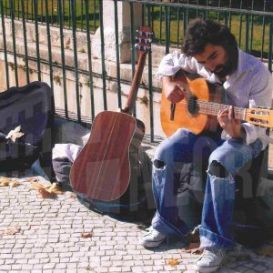Un músico ambulante toca la guitarra junto a la ría del Jardín del Parterre en Aranjuez