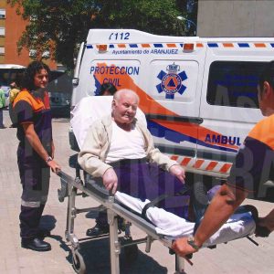 Dos voluntarios de Protección Civil trasladan a un hombre en una camilla a un colegio electoral en Aranjuez