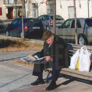 Un hombre lee el periódico en un banco en Aranjuez