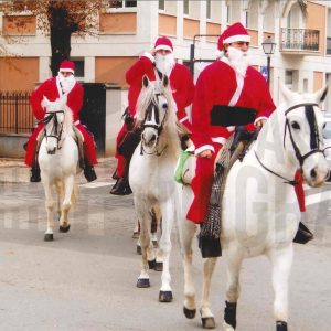 Varios hombres disfrazados de Papá Noel cruzan a caballo la Calle Stuart en Aranjuez
