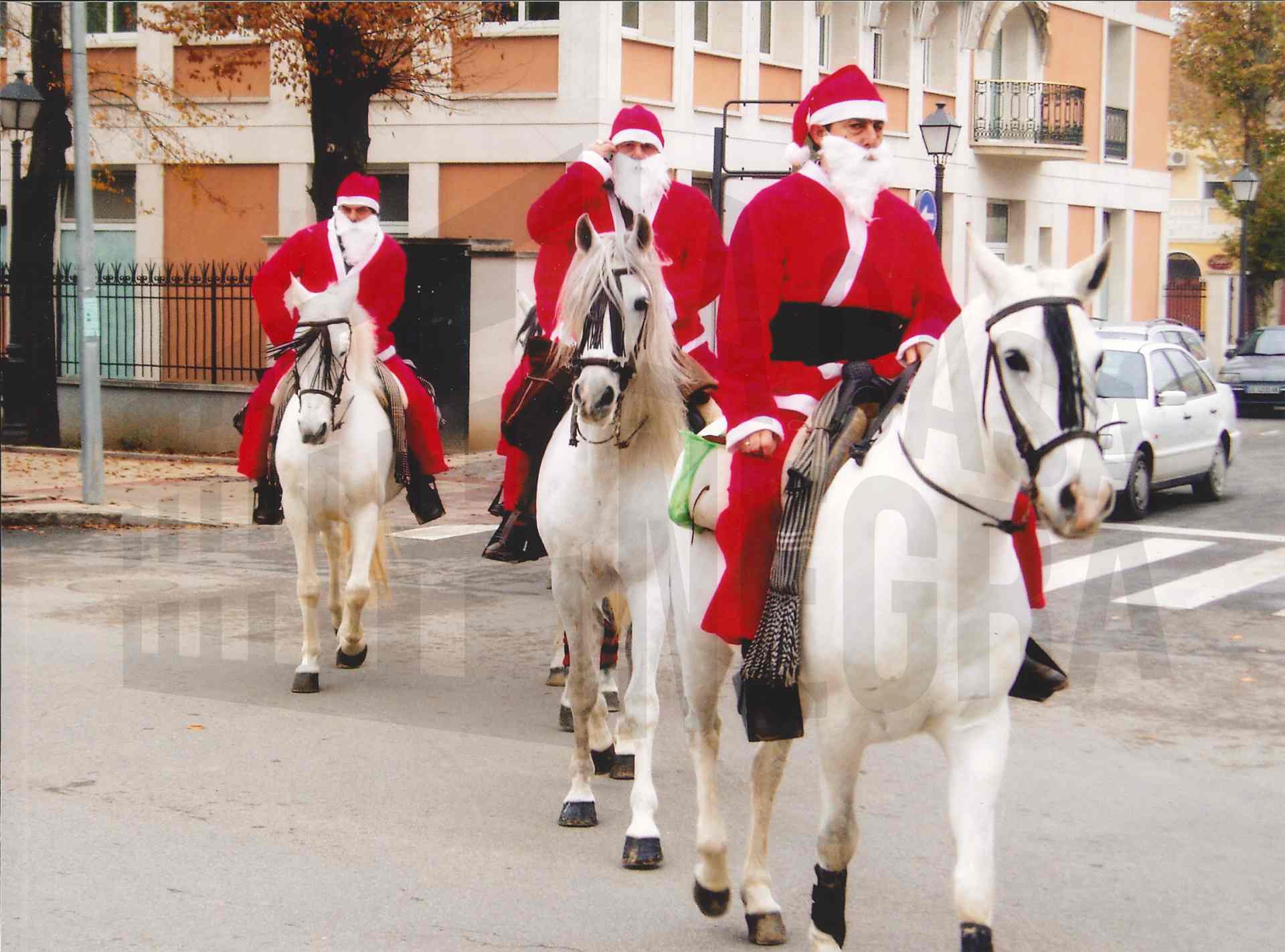 Varios hombres disfrazados de Papá Noel cruzan a caballo la Calle Stuart en Aranjuez