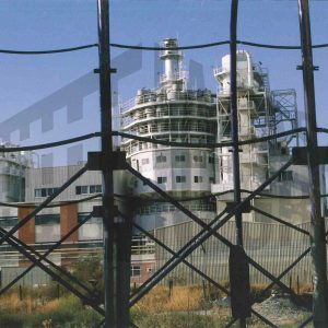 Torre de fabricación de la fábrica de Lever Ibérica en Aranjuez a través de una alambrada