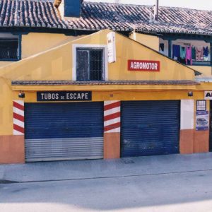 Edificio en la Calle Alpajés de Aranjuez con puerta de entrada a una corrala y un taller mecánico