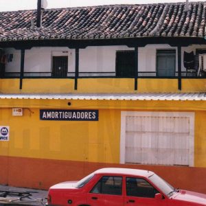Edificio en la Calle Alpajés de Aranjuez con puerta de entrada a una corrala y un taller mecánico