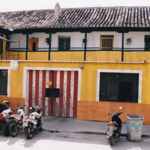 Edificio en la Calle Alpajés de Aranjuez con puerta de entrada a una corrala y un taller mecánico