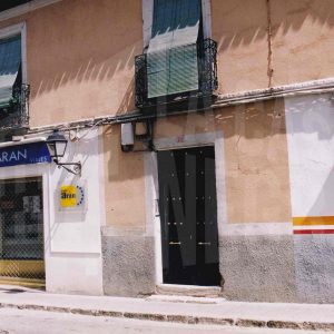 Edificio en la Calle San Pascual de Aranjuez con puerta de entrada a una corrala y una agencia de viajes