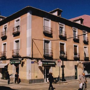 Edificios en la esquina de las calles Postas y Gobernador en Aranjuez con varios comercios y la puerta de entrada a una corrala