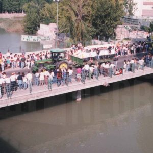 Público presenciando un desfile de carrozas sobre el Puente Barcas y el río Tajo, en Aranjuez