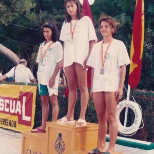 Diana García y otras dos nadadoras en el podio en  una piscina en Puerto Real