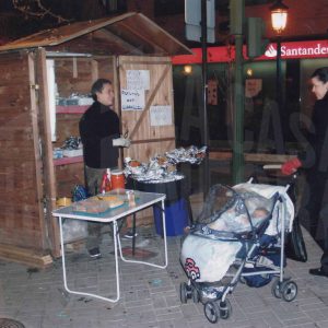 Personas en un puesto de venta de castañas y patatas asadas en Aranjuez