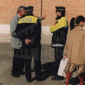 Una persona conversa con dos policías municipales en la Plaza de la Constitución de Aranjuez