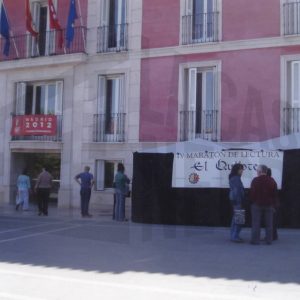 Varias personas y dos carpas para el IV Maratón de lectura del Quijote en  la Plaza de la Constitución de Aranjuez