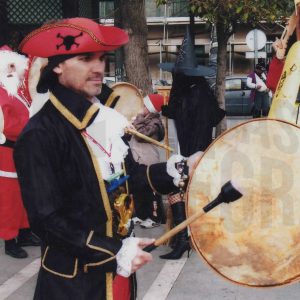 Varias personas disfrazadas tocando panderos en la Plaza de la Constitución de Aranjuez