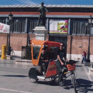 Triciclo turístico con pasajeros en la Plaza  de la Constitución de Aranjuez