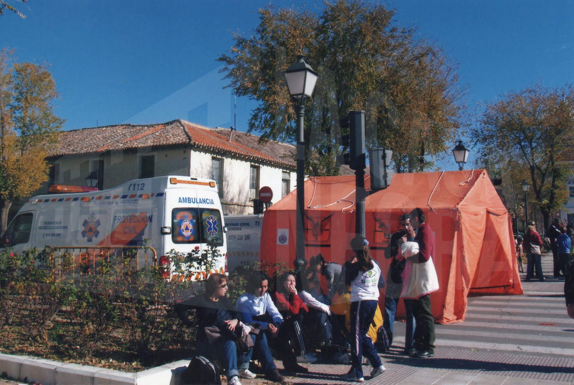 Varias personas junto a una ambulancia y un puesto de atención de Cruz Roja durante la Milla Urbana en Aranjuez