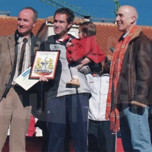 Un corredor, con un bebé en brazos, posa con su premio entre el Alcalde de Aranjuez, Jesús Dionisio Ballesteros, y  Philippe Gruau, director del Hipermercado E. Leclerc,tras la XXV Carrera Popular de Aranjuez